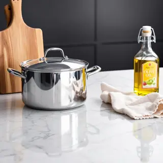 A kitchen counter with a stainless steel pot, a wooden cutti