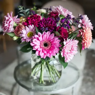 A vase of flowers on a glass table with a clear reflection v