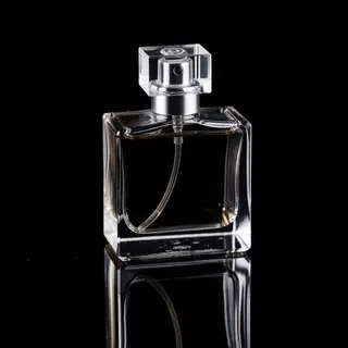 A clear glass perfume bottle on a reflective black surface w
