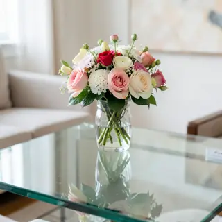 A vase of flowers on a glass table with a clear reflection v