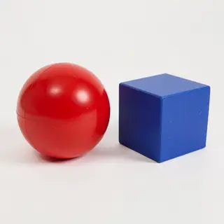A red ball and a blue cube sitting side by side on a white s