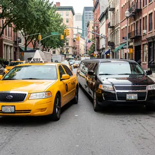A yellow taxi and a black limousine parked next to each othe