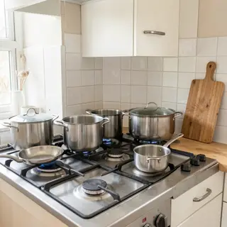 A kitchen with pots, pans, a stove, and a cutting board but 