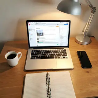 A desk scene: laptop in the center, coffee mug to the left, 