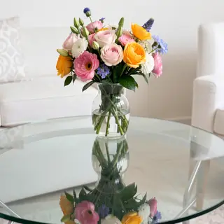 A vase of flowers on a glass table with a clear reflection v