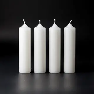 Exactly 4 white candles standing on a dark surface