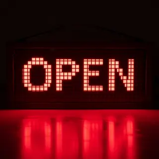 The word 'OPEN' displayed on a red LED sign with glowing pix