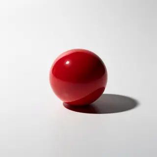 A red sphere on a white surface with a single shadow cast to