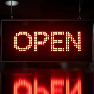 The word 'OPEN' displayed on a red LED sign with glowing pix