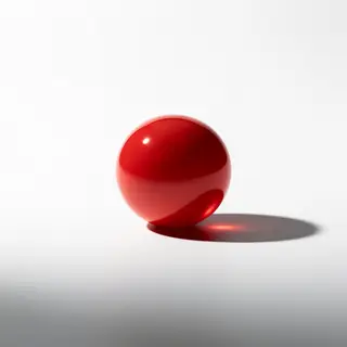 A red sphere on a white surface with a single shadow cast to