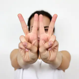 A person making a peace sign with their right hand, clearly 