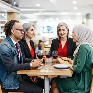 Four people at a dinner table: a bald man in a suit, a woman