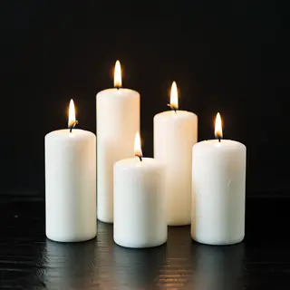 Exactly 4 white candles standing on a dark surface