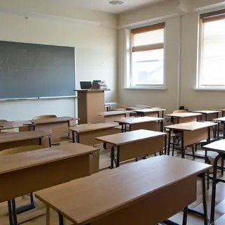 A classroom with desks and a chalkboard but no students