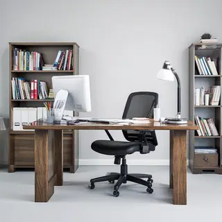 An office workspace with a desk, chair, bookshelf, and lamp 