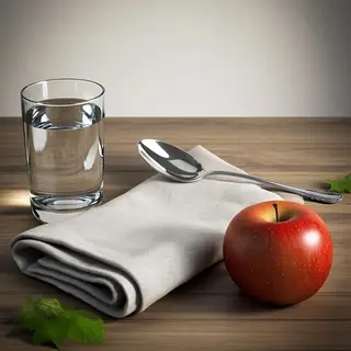 A still life on a wooden table featuring a clear glass of wa