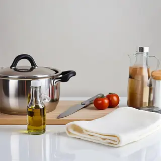 A kitchen counter with a stainless steel pot, a wooden cutti