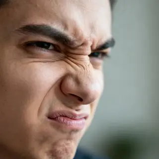 A close-up of a person's face showing clear disgust, nose wr