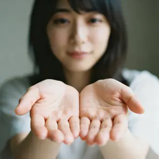 A woman holding her hands out in front of her palms-up, all 