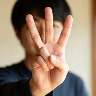 A person counting to three on their fingers, with index, mid