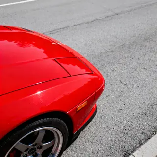 A bright red sports car parked on a gray asphalt road — the 