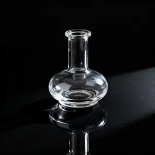 A clear glass perfume bottle on a reflective black surface w