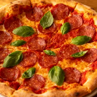 A pepperoni pizza with tomato sauce, basil, and crust but ab