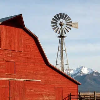 A landscape with a red barn in the foreground at large scale