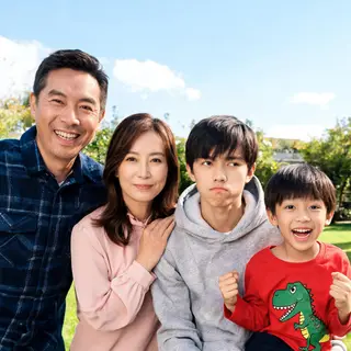 A family photo with four people: a father beaming with pride