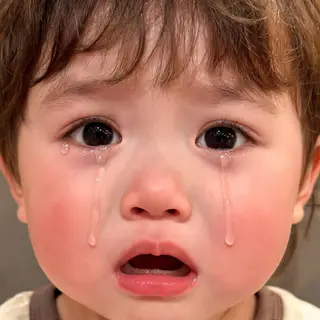 A 5-year-old child with round cheeks and large eyes, crying 