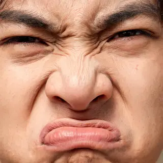 A close-up of a person's face showing clear disgust, nose wr