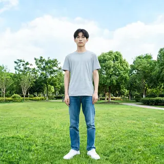A person standing in a neutral pose in a park, full body vis