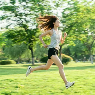 A woman mid-stride running through a park, hair and clothes 