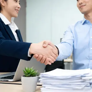 Two people shaking hands in a professional setting, all fing