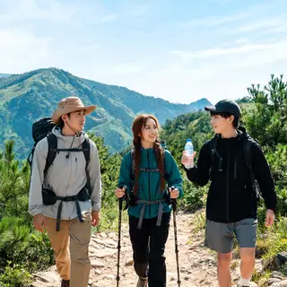 Three hikers on a trail: a man with a backpack and sunhat, a
