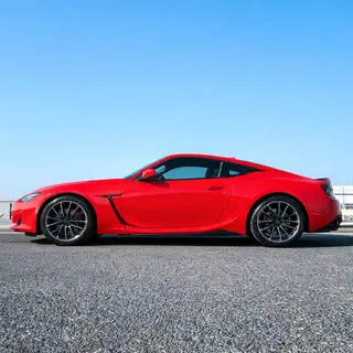 A bright red sports car parked on a gray asphalt road — the 