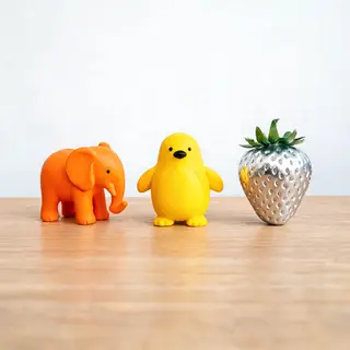 An orange elephant, a yellow penguin, and a silver strawberr