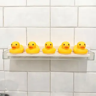 Exactly 5 yellow rubber ducks sitting in a row on a bathroom