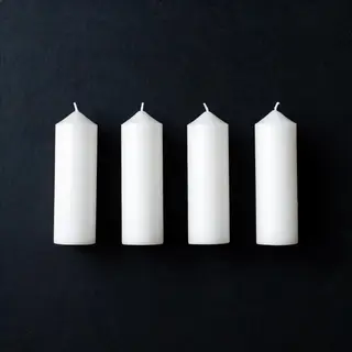 Exactly 4 white candles standing on a dark surface