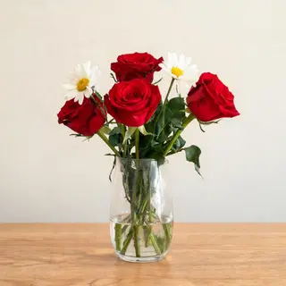 4 red roses and 2 white daisies in a glass vase on a table