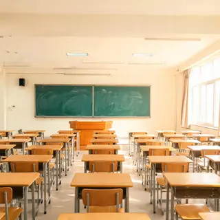 A classroom with desks and a chalkboard but no students