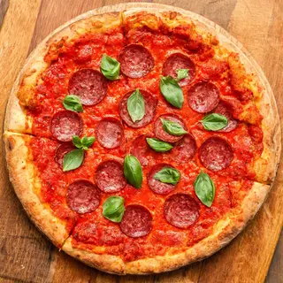 A pepperoni pizza with tomato sauce, basil, and crust but ab