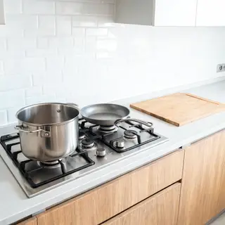 A kitchen with pots, pans, a stove, and a cutting board but 