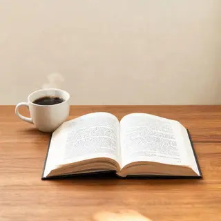 A coffee mug next to an open book on a desk