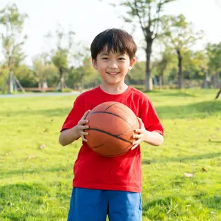 A child holding a basketball, both at correct relative sizes