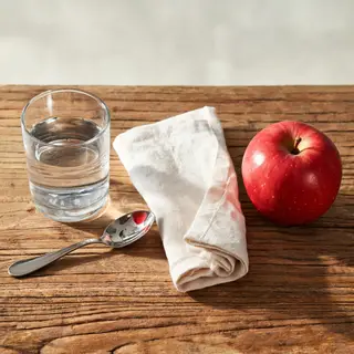 A still life on a wooden table featuring a clear glass of wa