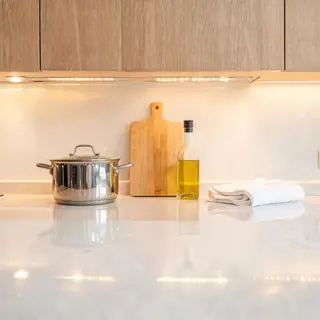 A kitchen counter with a stainless steel pot, a wooden cutti