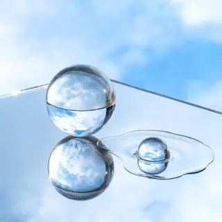 A clear glass sphere sitting on a mirror surface near a pool