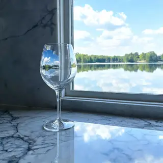 A crystal wine glass on a polished marble counter next to a 