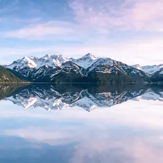 A mountain range reflected in a still alpine lake, with the 